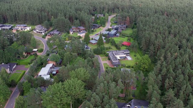 A rotating aerial view of Lauru kvartalas showing modern forest-edge homes, winding roads, and dense tree canopy, ideal for stories on eco-district planning and sustainable residential design.