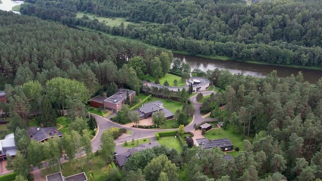Aerial shot revealing a riverside eco-neighbourhood bordered by dense forest, showing how modern homes and natural landscapes coexist in a carefully planned green settlement.