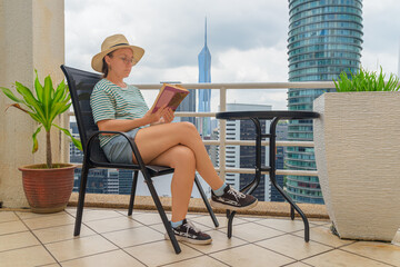 Woman is reading a book at scenic terrace among skyscrapers
