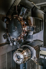 Fototapeta premium a complex industrial machine featuring multiple large, circular metal components with numerous bolts and gears. The machine parts are predominantly black and gray, with some silver accents