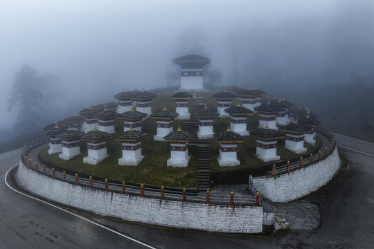 Aerial view of ethereal white chortens rise through the mist-shrouded landscape at Druk Wangyal Chortens, Dochula Pass, Bhutan.