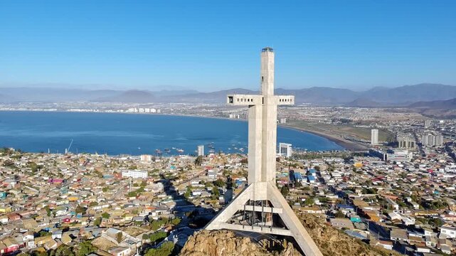 Aerial drone view of the massive Third Millennium Cross monument overlooking the city and ocean in Coquimbo