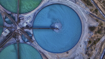 Aerial view of circular ponds filled with vibrant blue and green liquids, creating a stark contrast against the arid landscape, Tucson, Arizona, United States.
