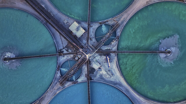 Aerial view of circular ponds with turquoise water and industrial structures create a mesmerizing geometric pattern from above, Tucson, Arizona, United States.