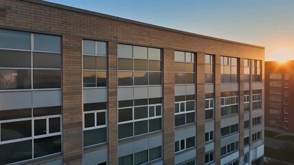 Modern office building facade with reflective windows against a soft sunset sky.