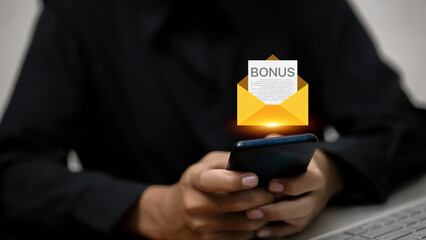 Businessman holding smartphone with virtual email envelope showing bonus letter.