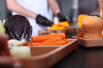 Fresh peeled carrots on the table. Vegetables for cooking vegetarian dishes. Healthy food. The cook's hands are out of focus. Cooking.