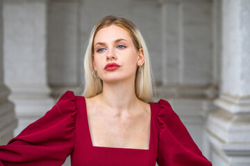 Fototapeta premium Portrait of a young beautiful blonde girl in an evening burgundy dress