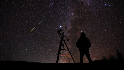 Amateur astro-photographer with a camera on a tripod photographing night sky with stars, planets, Moon and other celestial objects. © astrosystem