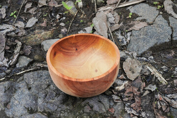 A wooden round bowl placed on a rough stone surface. Flatlay high top angle view.