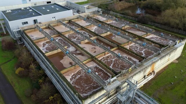 Aerial view of a sewage treatment plant showcasing the brown murky water and foamy textures, King's lynn, England, United Kingdom.
