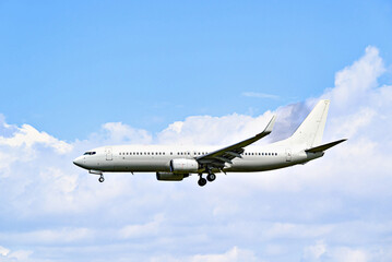 Passenger plane landing at the airport, under a blue sky with white clouds	
