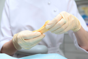 The doctor holds in his hands a mass for making dental casts. Material for making dental casts. A mass for making dental casts in dentistry. Dental impression.