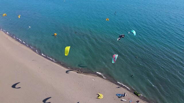 Aerial view of kitesurfers riding the turquoise waves and sandy beach of Velika Plaza, creating a vibrant contrast against the shore, Ulcinj Municipality, Montenegro.