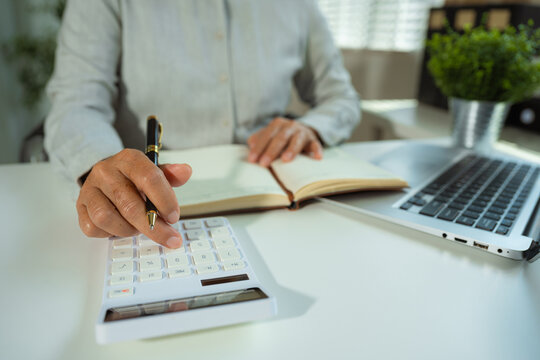 woman use the calculator and take notes with calculations about the expenses at the office. Prepare to submit annual tax.