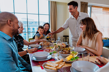 Family and friends reunion at home. Multi-generational family gathering having lunch at home