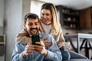 Happy couple relaxing at home with coffee, enjoying online shopping and shared digital experiences