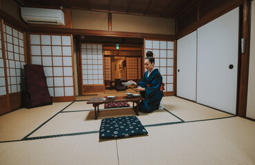 Woman wearing a kimono performing the chado ritual, preparing and serving ceremonial matcha tea in...