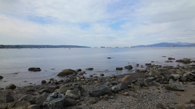 Gimbal wide dolly shot of the rocky shoreline along English Bay in Vancouver, British Columbia, Canada. 4K at 30 FPS
