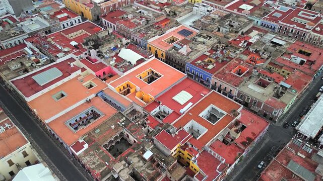 High aerial over Puebla revealing tight colorful rooftop patterns and warm tones across the urban layout