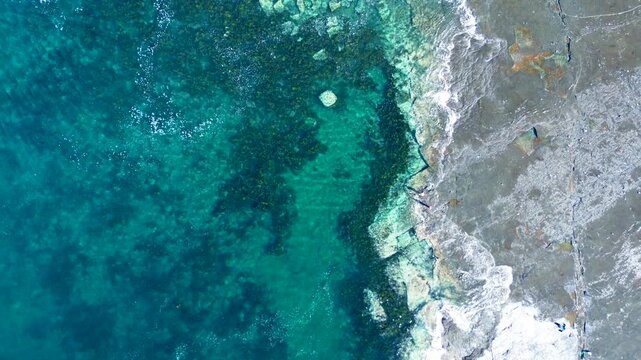 Drone aerial landscape of waves breaking along seaweed sandbar reef in ocean bay inlet on beach coastline and rocky headland of Gerroa Gerringong South Coast Australia travel tourism fishing surfing