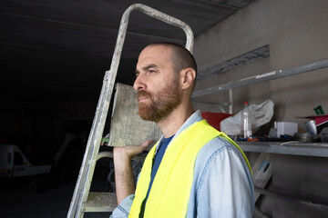 Construction worker carrying a ladder inside a workshop