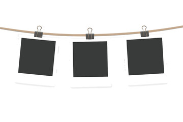 Three blank instant film prints hanging on a rope with clips