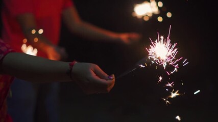 Playful children waving sparkler firework and enjoying celebration. People celebrates New Year's Eve. Happy, joyful people spinning sparklers. Diwali, Christmas and New Year celebration concept.
