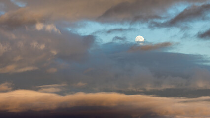 The sky is cloudy and the moon is shining brightly