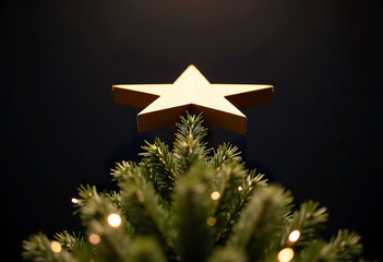 A view from below of a Christmas tree in the shape of a star against a dark ceiling, with bokeh-style lights below.