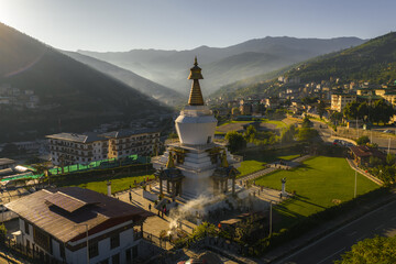 Aerial view of the Memorial Chorten glowing in the morning sun against a backdrop of misty mountains and the city, Thimphu, Bhutan.