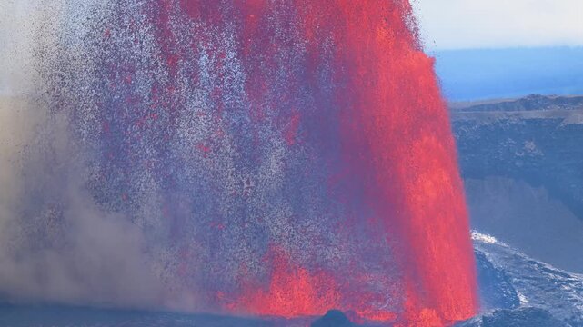 Aerial view of molten lava exploding from a volcano, contrasting against the dark landscape and creating a dramatic, fiery scene, Kilauea, Hawaii, United States.