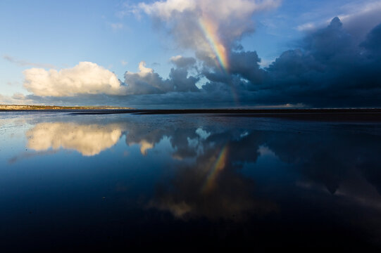 A dramatic cloudscape, skyscape, seascape and beachscape reflection scene from Red Wharf Bay featuring a rainbow, Area of Outstanding Natural Beauty, Anglesey, Gwynedd