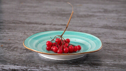 Red berries on turquoise dish, weathered wood background