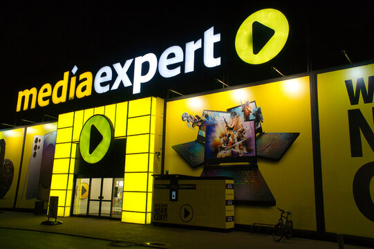 Sklep Media Expert w nocy, podświetlane logo na fasadzie budynku:  Legnica, Dolny Śląsk, Polska - 8 grudzień 2025 r.