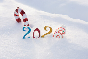 Candles - numbers, and Christmas tree decorations are buried in white snow and form the inscription 2026. The concept of New Year and Christmas