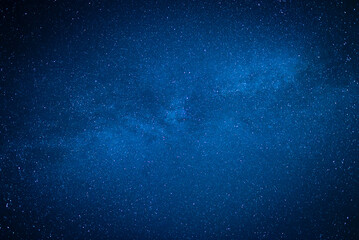 Deep blue high-resolution view of the night sky densely populated with countless stars and the glowing the Milky Way galaxy