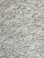 White rough plaster wall texture with irregular surface pattern.