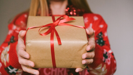Girl or a woman in a Christmas sweater with a gift box. Christmas present.