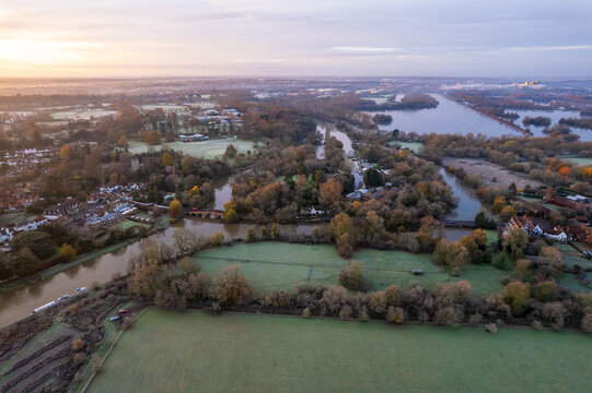 Aerial view of the River Thames winding through Sonning's green fields and trees, a tapestry of waterways and autumnal hues under a soft sky, Sonning, Oxfordshire, United Kingdom.