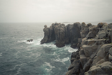 Cloudy morning and mist over the granite cliffs of Punta Moras