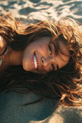 A beautiful young woman on the beach lies on the sand and smiles
