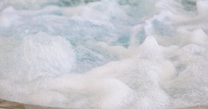 Macro view of water bubbles and foam swirling in a jacuzzi spa. Highlights texture, relaxation and hydrotherapy concept.