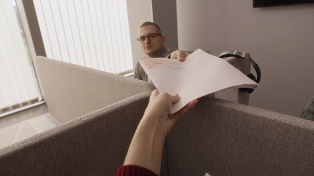 POV shot of unrecognizable office employee passing document with sticker note to colleague through partition wall, showcasing teamwork, collaboration, and communication in modern workspace