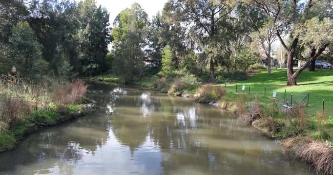 Edgars Creek flowing through a green suburban park. Natural waterways in Reservoir, Melbourne, Australia. Concept of urban creek restoration, local waterway ecosystem, public park environment