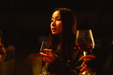 Young woman enjoying an evening drink while seated at a dimly lit gathering