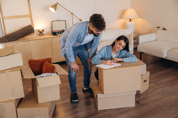 Busy by writing the information. Couple reviewing documents and planning their new home after moving