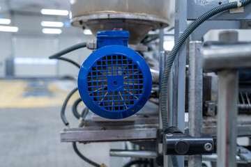Electric motor with blue fan cover on industrial extrusion machine in factory hall