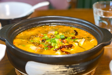 Close-up fish soup with pickled mustard greens in a black bowl. Delicious Chinese food.