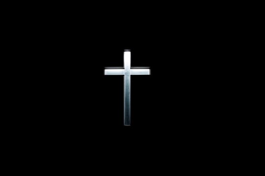 Cross stands alone against black background at night